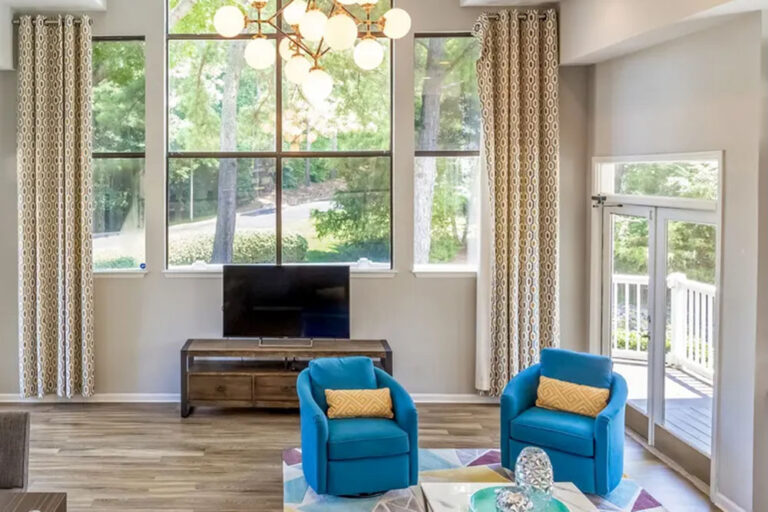 Clubhouse lounge with blue swivel chairs, TV and tall windows