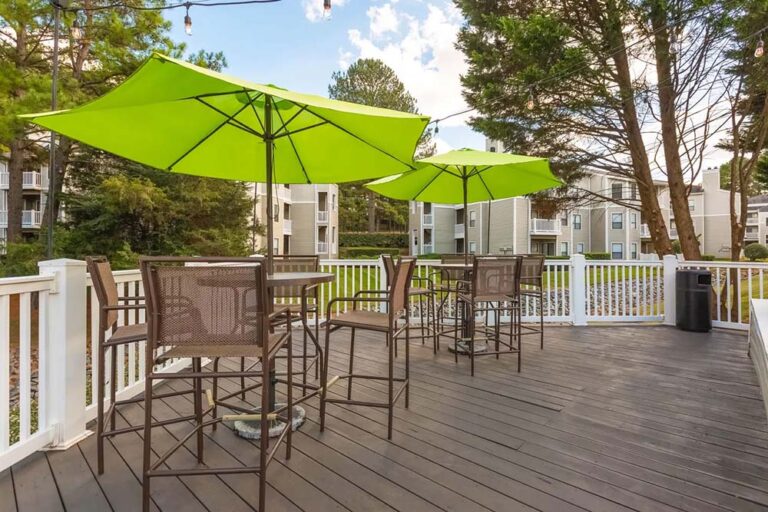 Outdoor deck with bar-height tables, green umbrellas and string lights